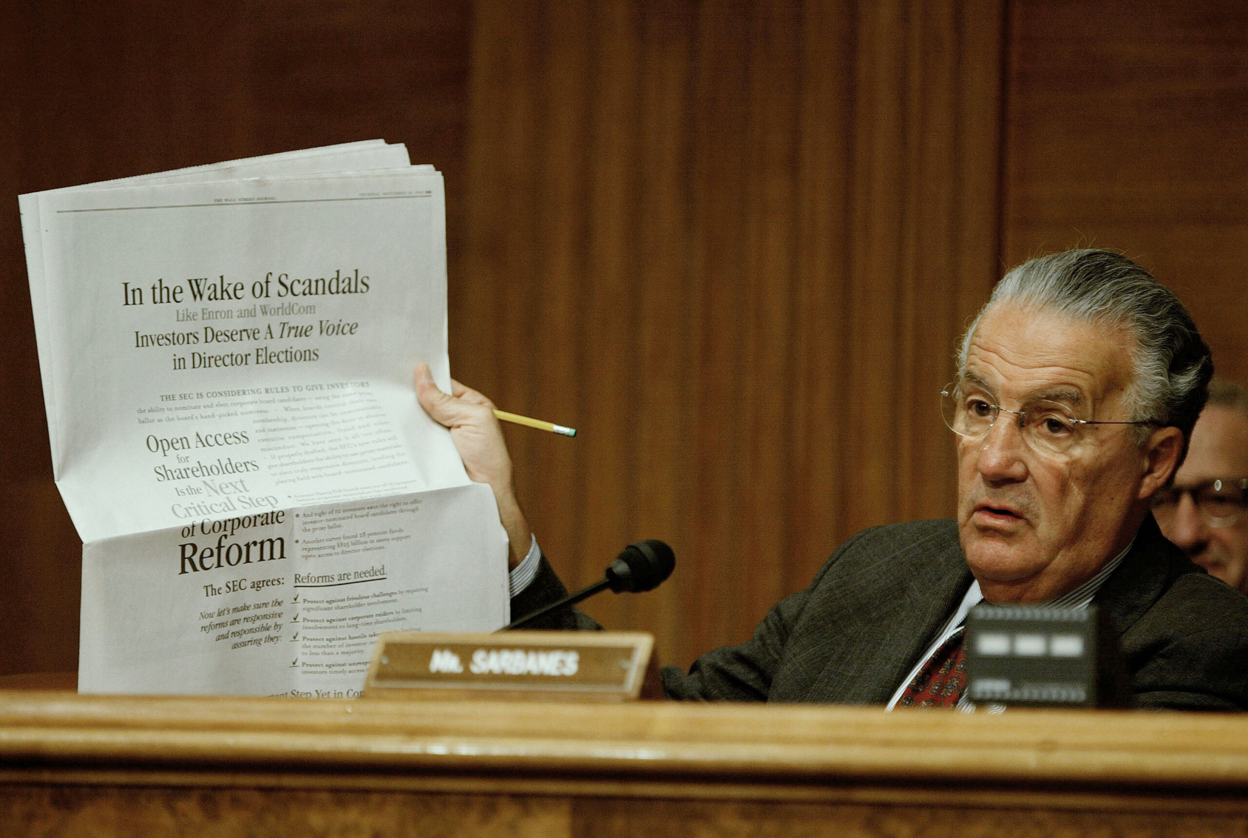 Paul Sarbanes holds up newspaper during Capitol Hill hearing
