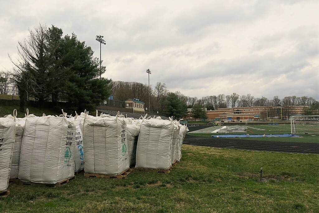 bags of field infill at the edge of a synthetic turf field