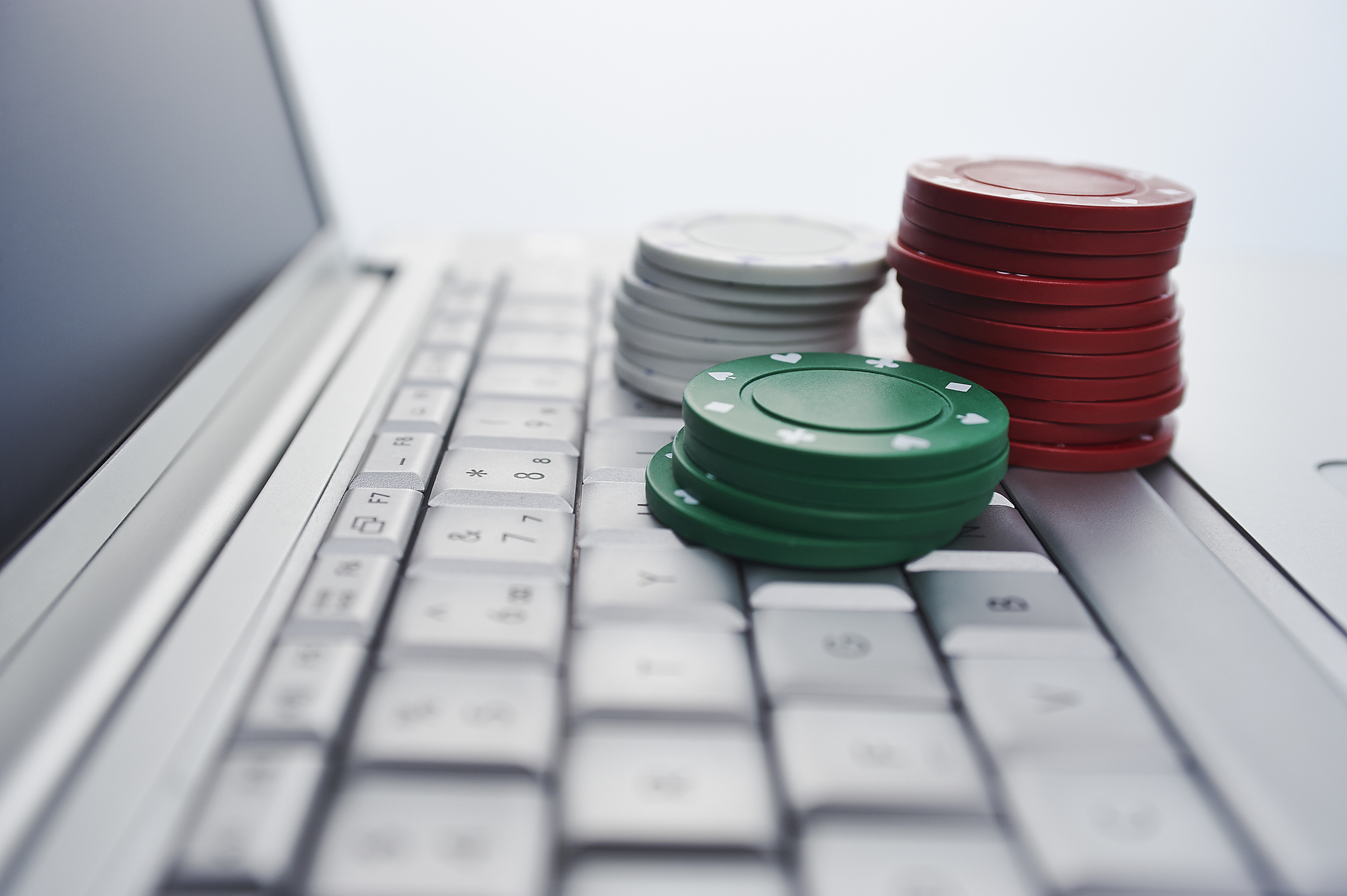 Three small stacks of betting chips are piled on a laptop keyboard